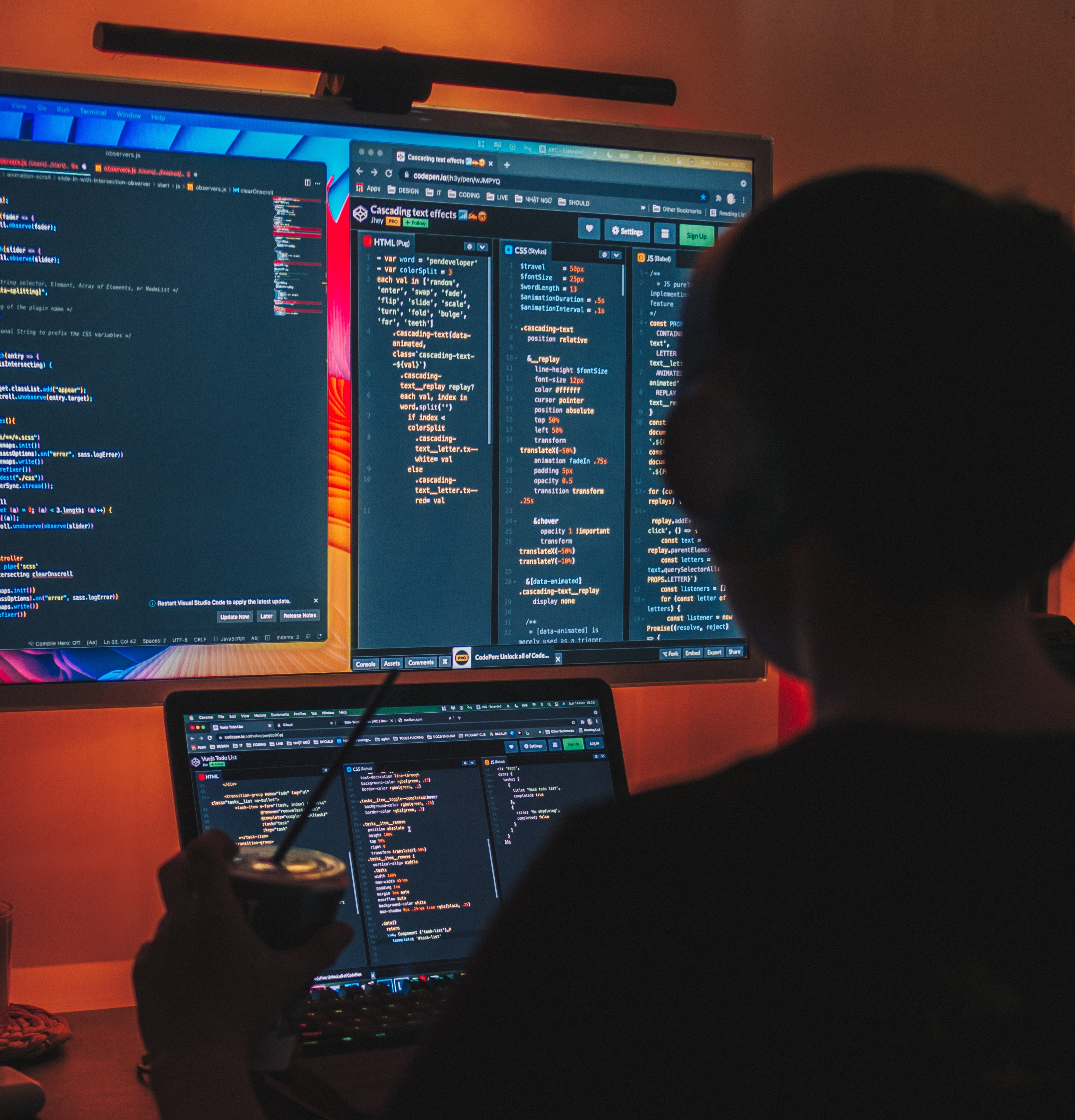 A software engineer sits in a dark room, with red illuminations, working on backend code